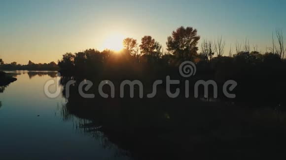 空中无人机镜头日落时分在平静的河流上空飞行视频的预览图