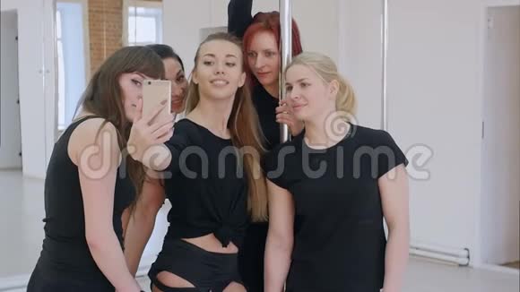 一群漂亮的年轻女性在钢管舞课上用智能手机自拍视频的预览图