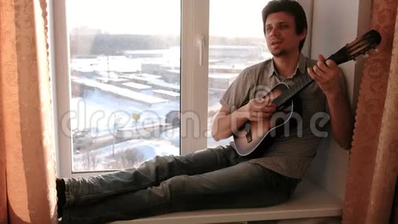 演奏乐器男人坐在窗台上弹吉他视频的预览图