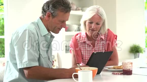 中老年夫妇看着数字平板早餐视频的预览图