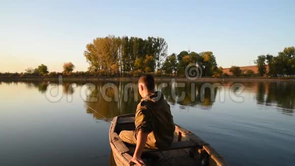 一个渔夫正在船上钓鱼一个年轻人正在河上的木船里钓鱼视频的预览图