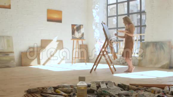 女孩艺术家在画架上的画布上作画并在艺术工作坊中担任调色板视频的预览图