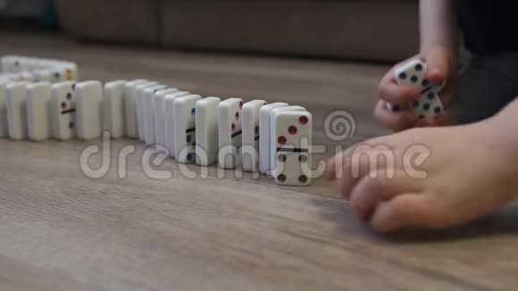 一个孩子在家里地板上玩多米诺骨牌的特写镜头视频的预览图