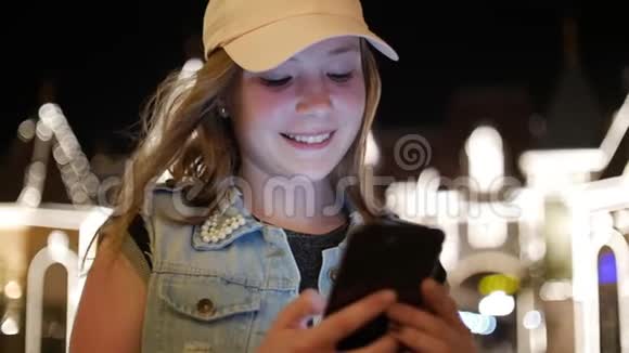 在一个夜晚的城市里一个迷人的少女使用手机在街上行走背景是夜晚视频的预览图