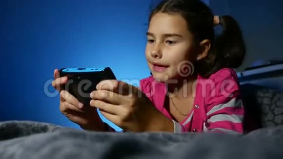 青少年女孩玩儿童便携式电子在线游戏一个控制台孩子晚上在室内视频的预览图