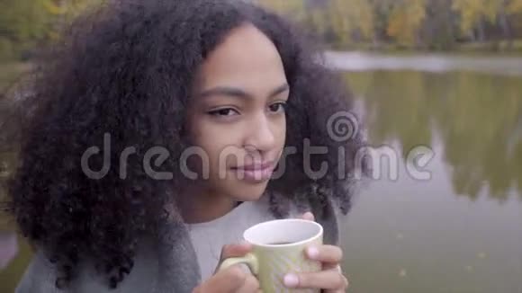 可爱的黑女孩裹着羊毛格子喝着热茶视频的预览图