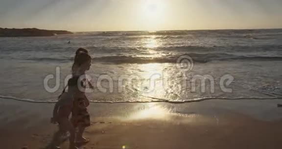 日落时三个孩子在海滩上奔跑的照片视频的预览图