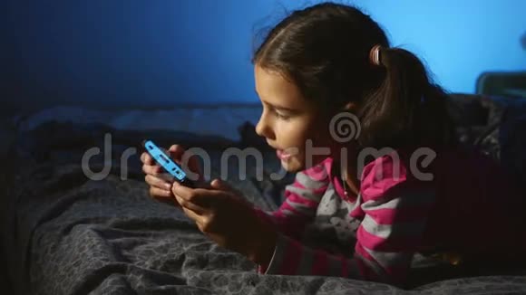 青少年女孩在网上玩手提电子游戏晚上在室内玩游戏机视频的预览图