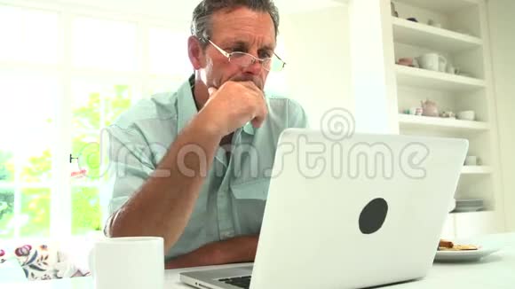 中年男人用笔记本电脑吃早餐视频的预览图