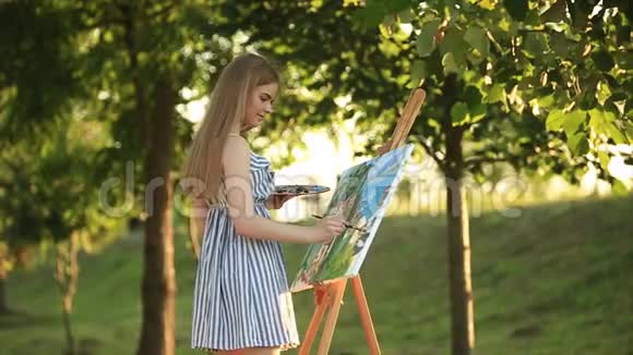 美丽的女孩艺术家站在公园里拿着颜料调色板视频的预览图