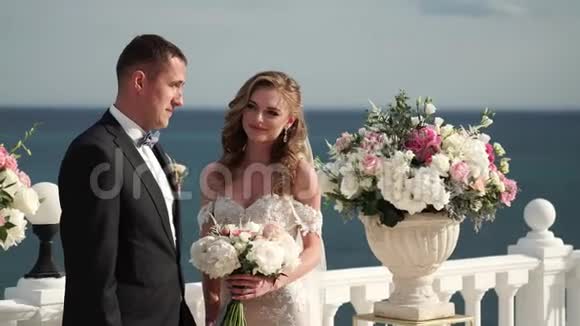 婚礼上的新娘和新郎一对相爱的年轻夫妇站在拱门前海边的婚礼视频的预览图