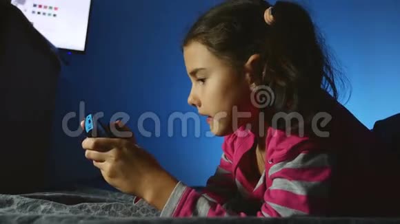 青少年女孩在室内玩手提儿童电子游戏晚上玩游戏机视频的预览图