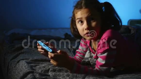 青少年女孩在室内玩手提电子游戏晚上在网上玩游戏机视频的预览图