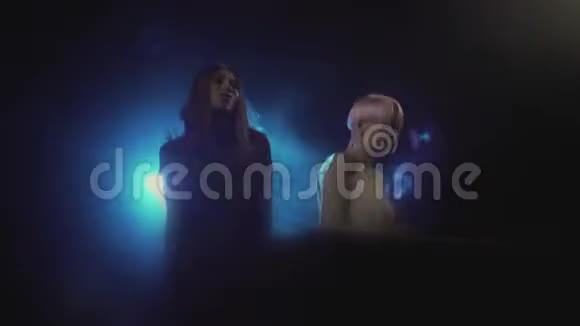 两位年轻的美女DJ在夜总会的混合控制台播放音乐视频的预览图