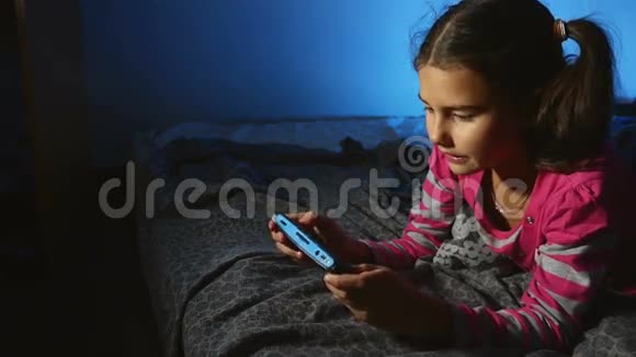 一个女孩在室内玩手提电子游戏一个晚上在网上游戏机的孩子视频的预览图