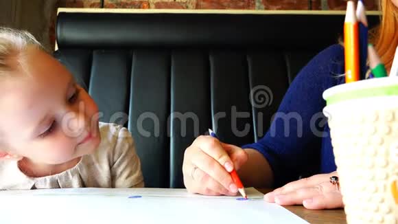 母亲和女儿在桌旁的纸上画红铅笔视频的预览图