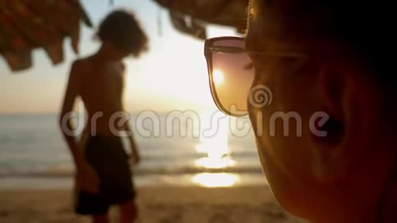 美丽的阳光灿烂的日落在海上透过太阳镜观看戴太阳镜的女人看着大海上的日落视频的预览图