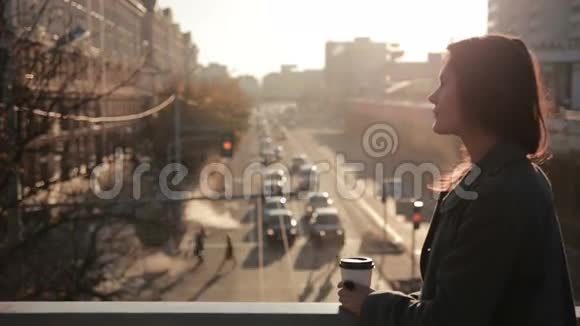美丽的女人在城市桥上喝咖啡视频的预览图