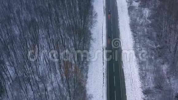 冬季穿过冬季森林的道路上的交通鸟瞰图视频的预览图