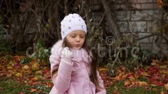 穿着粉红色外套躺在秋叶上的小女孩视频的预览图