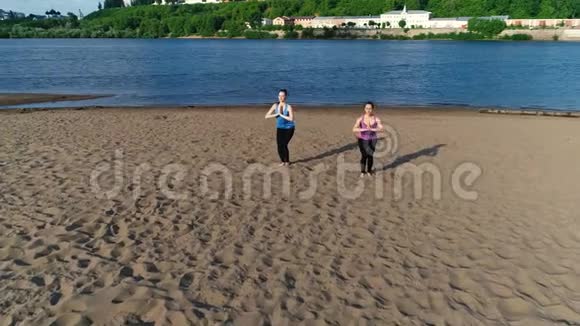 两个女人在城市河边的沙滩上做瑜伽美丽的景色视频的预览图