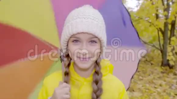 秋天公园里穿着黄色雨衣带着彩色雨伞的漂亮女孩视频的预览图