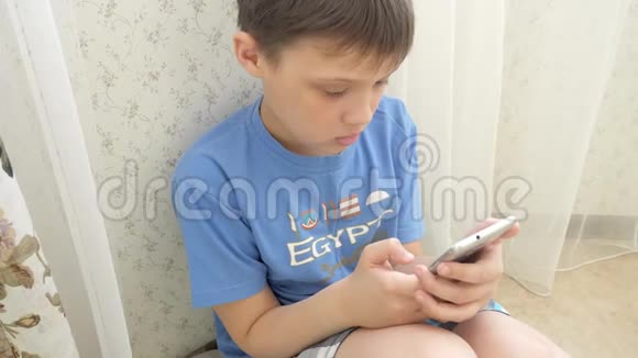 青少年在家中坐在地板上兴奋地玩智能手机游戏视频的预览图