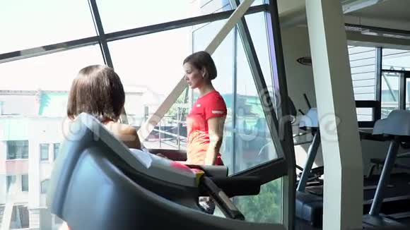 漂亮的白种人女孩在运动健身房的跑步机上跑步视频的预览图