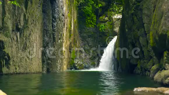 雨林中的山瀑布瀑布流出来的水流在河中的大石头上视频的预览图