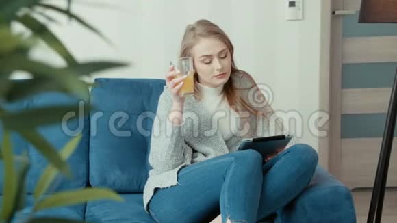 年轻女子坐在沙发上用平板电脑视频的预览图