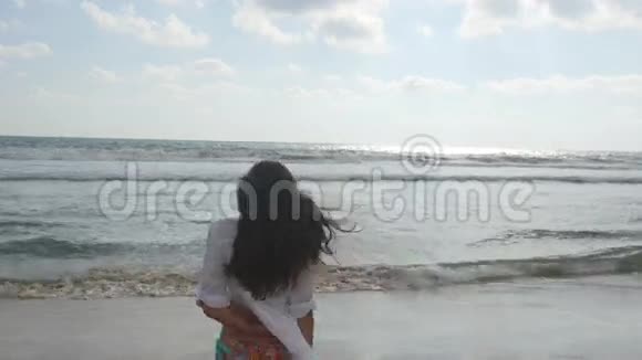 穿比基尼和衬衫的快乐女人在海水的海滩上散步年轻漂亮的女孩享受生活视频的预览图