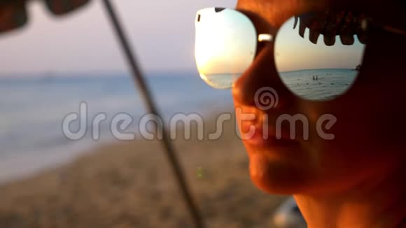 美丽的阳光灿烂的日落在海上透过太阳镜观看戴太阳镜的女人看着大海上的日落视频的预览图
