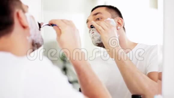 带安全剃刀的男人在浴室刮胡子视频的预览图
