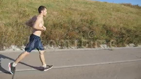 年轻的壮汉在美丽的大自然中在路上奔跑男子跑步运动员在乡村公路锻炼训练中慢跑视频的预览图