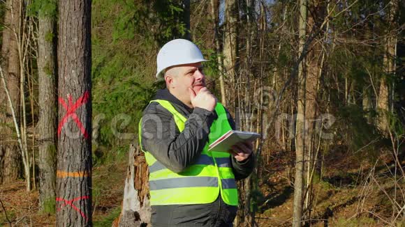 思虑周到的森林工程师与平板电脑附近的树木视频的预览图