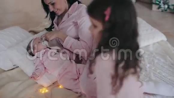 母亲和女儿穿着粉红色睡衣的新生婴儿在平安夜视频的预览图