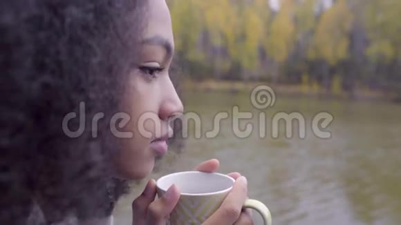 可爱的黑女孩裹着羊毛格子喝着热茶视频的预览图