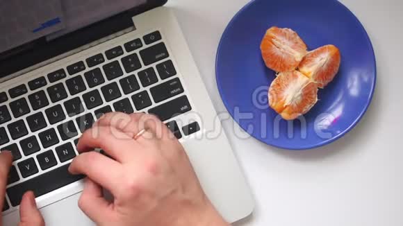 一个男人正在用笔记本电脑工作在键盘上键入文本不时地吃着一只躺在碟子上的普通话从一个视频的预览图