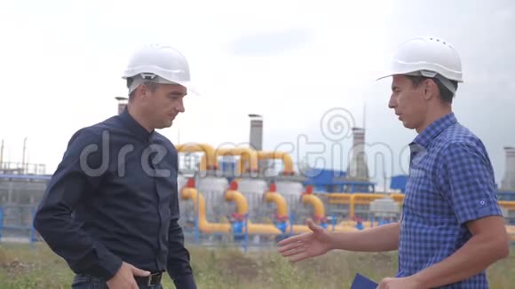 团队合作行业产气站理念慢动作视频两名戴头盔的工程师在煤气上握手视频的预览图
