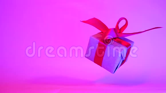 礼品盒红色丝带旋转霓虹灯紫色背景360度旋转无缝环零重力悬浮视频的预览图