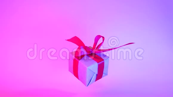 礼品盒红色丝带旋转霓虹灯紫色背景360度旋转无缝环零重力悬浮视频的预览图