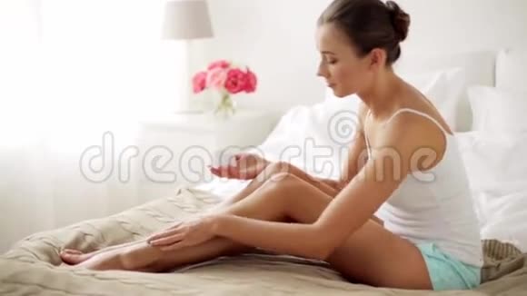 漂亮的女人在家里给她的腿抹奶油视频的预览图