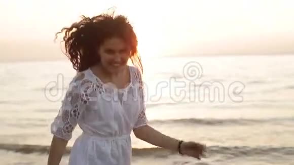 美丽快乐微笑的女人在海上日落慢动作视频的预览图