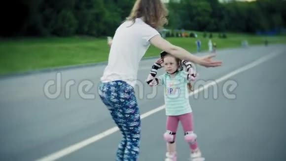 妈妈帮助女儿在溜冰公园滑冰视频的预览图