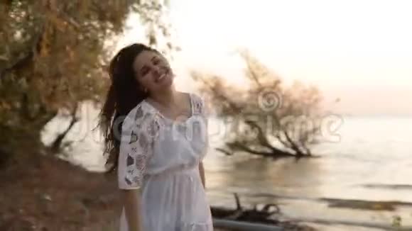 美丽快乐微笑的女人在海上日落慢动作视频的预览图