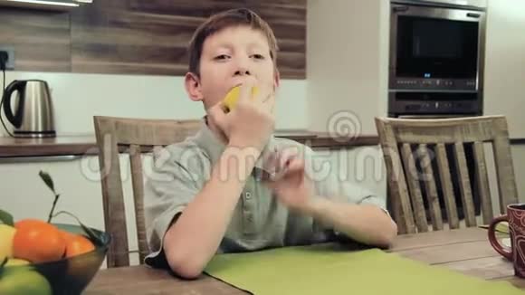 坐在厨房桌子旁吃苹果的男孩视频的预览图