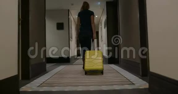 带着手提箱的女人走在酒店走廊里视频的预览图