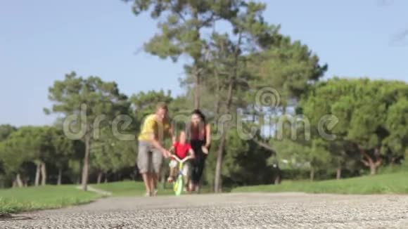 父母教儿子在公园骑自行车视频的预览图