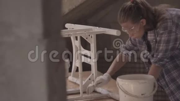 女孩木匠设计师装饰师在一个修复旧家具的车间工作视频的预览图