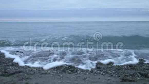 日落时的卵石海滩波浪飞溅碎成飞沫4k慢动作视频的预览图